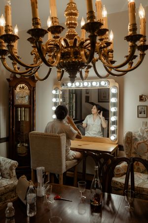 Wedding preparations in an elegant dressing room with antique chandeliers and mirrors.