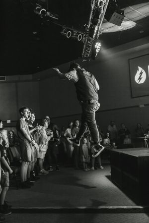 Performer jumping high on stage during energetic concert performance.