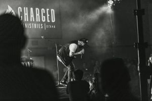 Concert performer silhouetted against foggy stage with 'Charged' text visible.