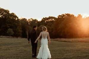Couple walking away into the sunset across an open field after their wedding ceremony.