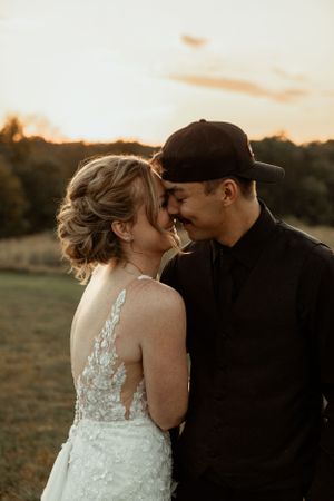 A tender moment between newlyweds at sunset against a rural backdrop, highlighting intimate connection and romance.