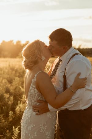 A romantic sunset portrait of a bride and groom embracing in a golden field.