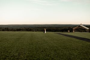 A distant view of a wedding venue on a hilltop with rolling green landscape.