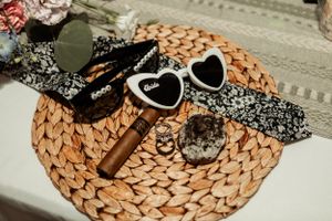 Wedding accessories including heart-shaped sunglasses and floral details on a woven placemat.