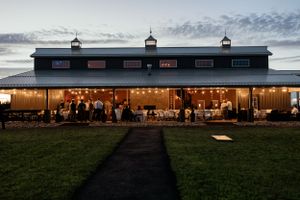 A rustic barn wedding reception venue lit up at twilight with guests inside.