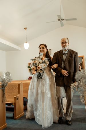 A traditional church wedding ceremony with wooden pews and a vaulted ceiling with white walls.