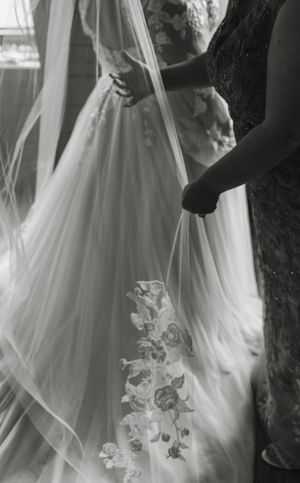 Black and white detail shot of elaborate wedding dress lace and flowing veil.