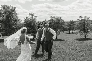 A couple dances playfully in a sunny field with a flowing veil catching the breeze.