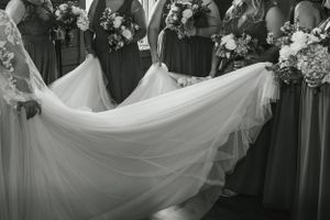 Black and white photograph showing bridesmaids holding the train of a wedding dress.