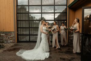 Wedding party gathers outside modern venue with glass windows.