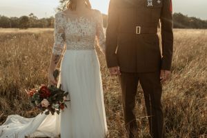 A sunset wedding portrait in a golden field with soft backlighting.