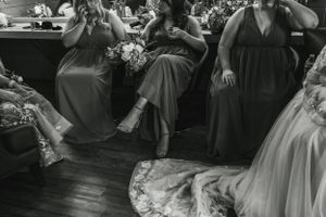Black and white photo of wedding guests seated at reception with dress train in foreground.