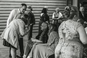 Vintage style black and white photo of wedding guests mingling at rustic venue.