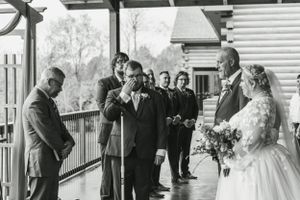 Black and white photo of outdoor wedding ceremony on rustic wooden porch.