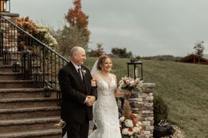 A wedding ceremony on stone steps decorated with floral arrangements as pair descends together.