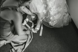 A black and white detail shot of wedding shoes being fastened.