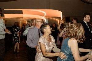 Wedding reception guests dancing and celebrating on a wooden dance floor.