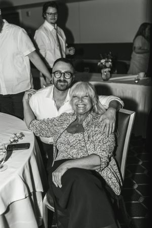 Candid black and white photo of guests relaxing at a wedding reception table.