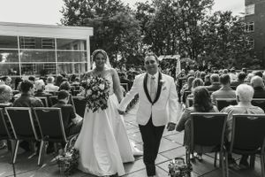 Couple walking down the aisle at an outdoor ceremony with seated guests.