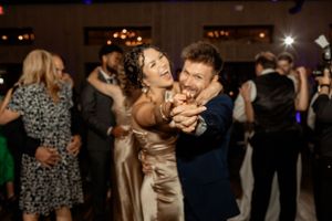 A joyful couple shares an intimate dance moment at their wedding reception on a dimly lit dance floor.