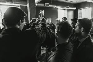 A black and white candid photo of a gathering with cameras and phones raised.
