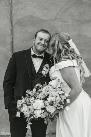 Black and white portrait of newlyweds sharing joyful moment with elegant florals.