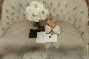 Wedding details featuring a white floral bouquet and accessories arranged on a tufted couch.