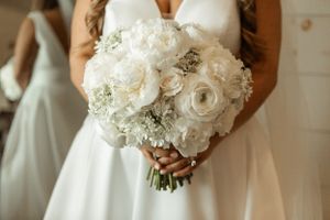 A stunning white bridal bouquet featuring roses, ranunculus, and delicate crystal accents.