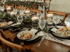 An intimate wedding table setting with glowing candles, greenery, and elegant place settings.