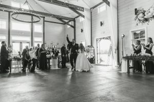 Black and white photo of wedding guests mingling in an elegant barn reception venue.