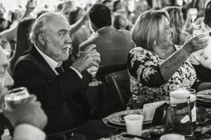 Black and white candid photo of wedding guests enjoying dinner at a reception.