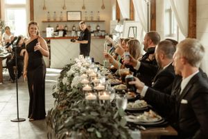 A celebratory reception dinner space with elegant floral centerpieces and guests seated at a long banquet table.