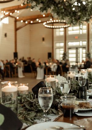 An elegant wedding reception venue with string lights, decorated tables, and candle centerpieces.