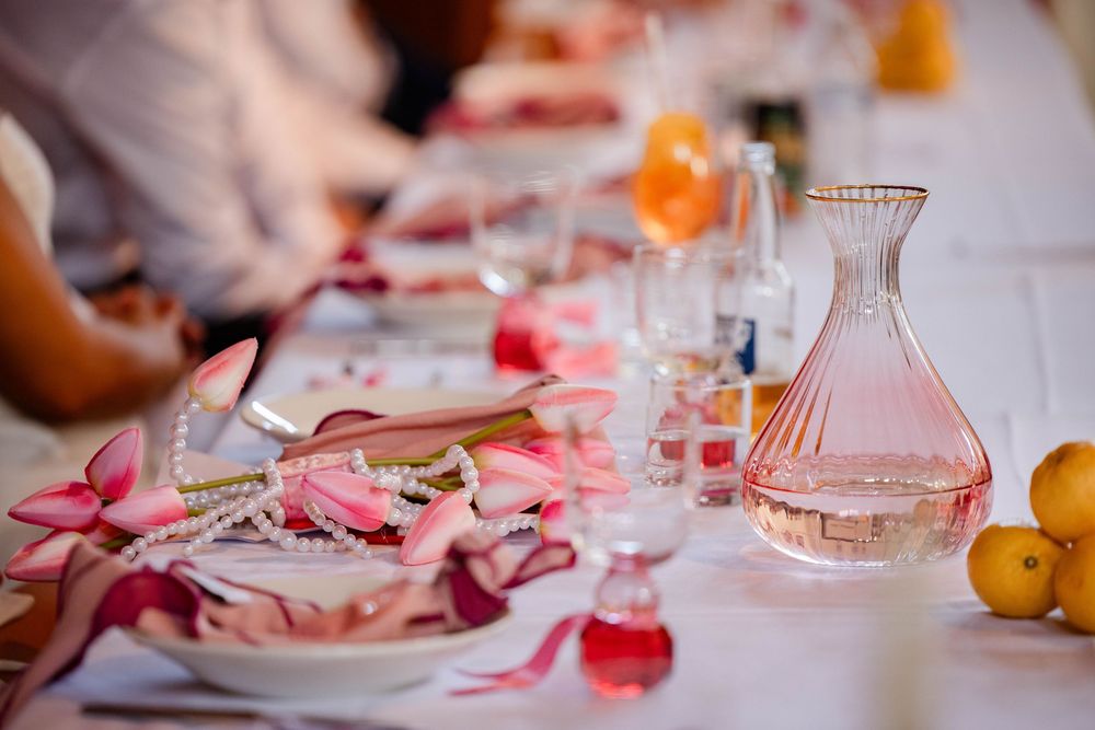 Elegant table setting with pink decor, glassware and citrus fruits.