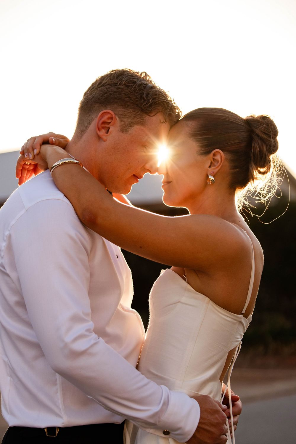 Intimate sunset moment between couple in formal wedding attire.