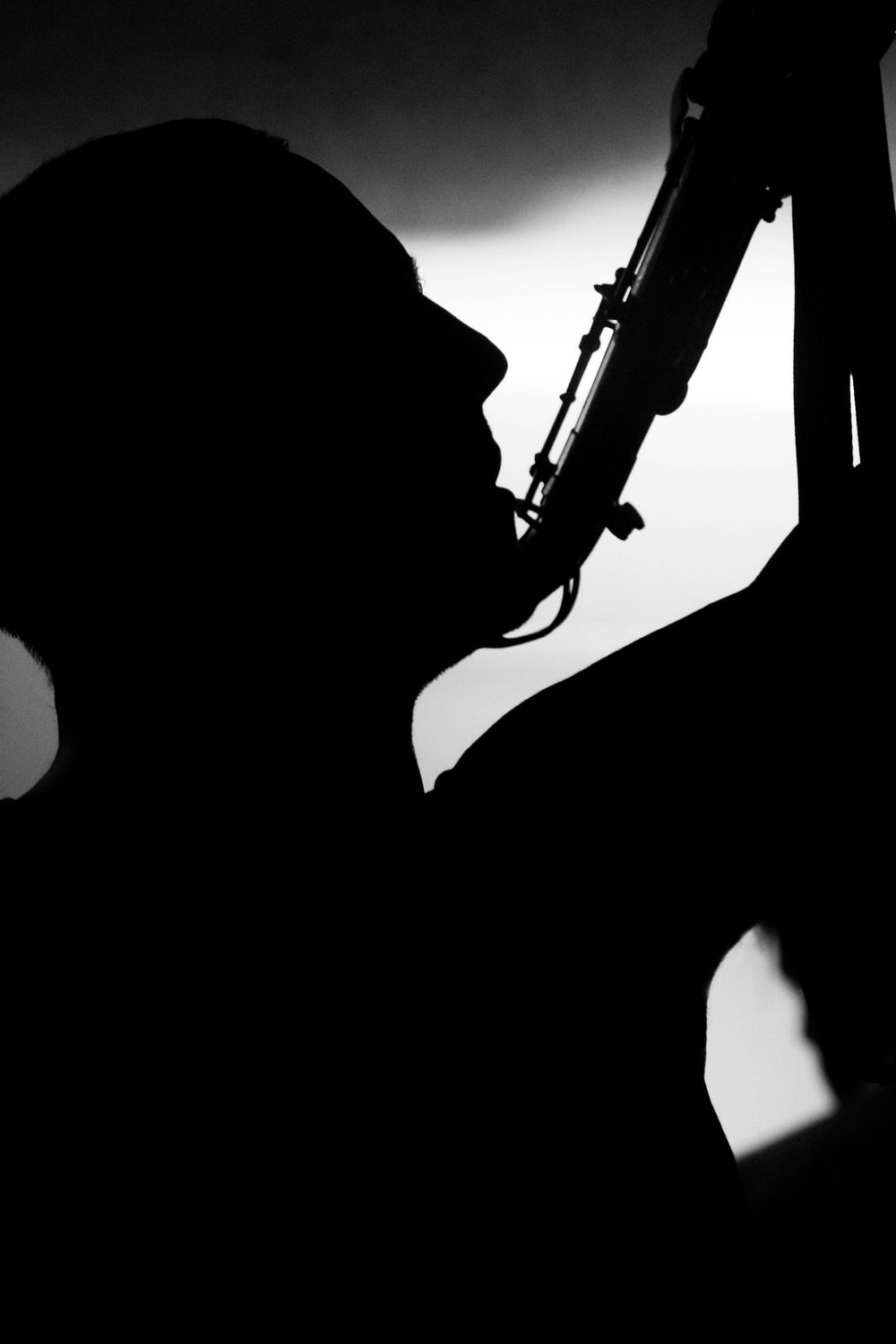 Silhouette of a musician playing a saxophone against a dramatic black and white background.