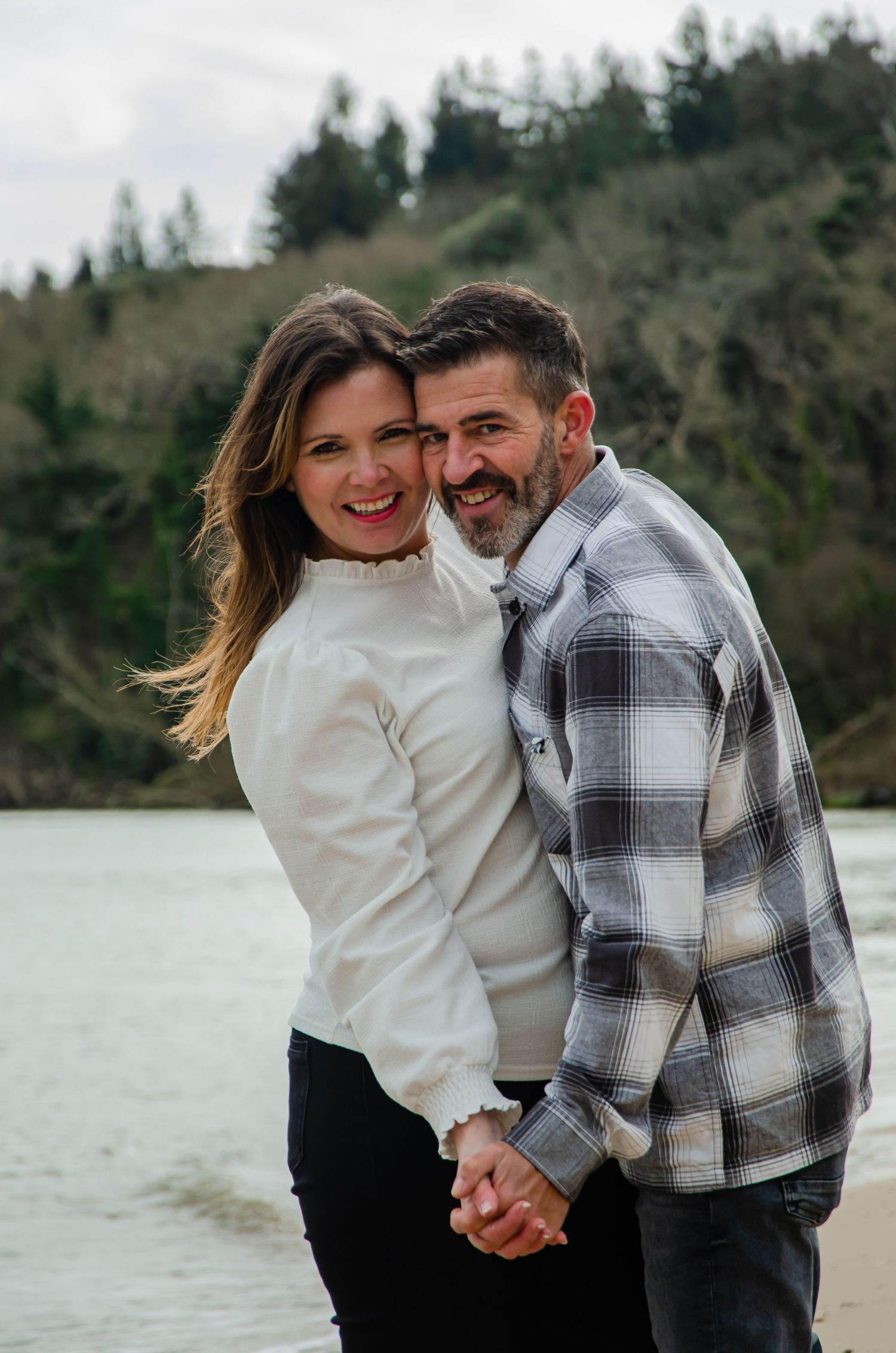 A romantic couple shares an intimate moment while holding hands on a serene beach.