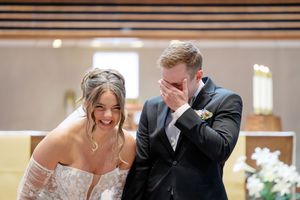 A couple shares an emotional moment while sitting together during their wedding ceremony at a church.