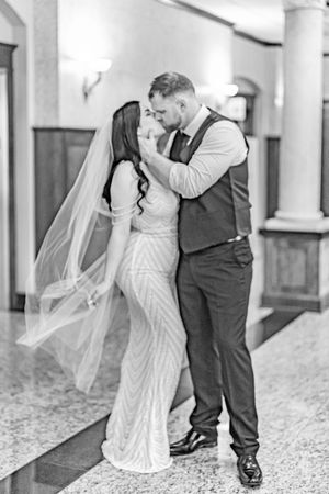 A romantic black and white wedding photo showing a couple sharing a tender moment in an elegant hallway.