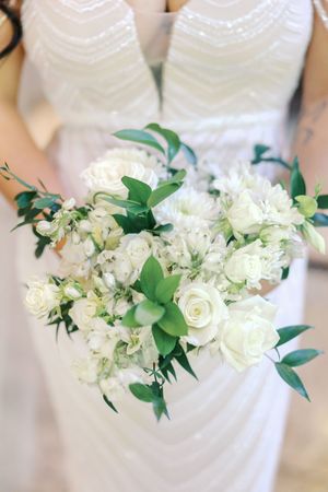 White and cream floral bouquets with green foliage arranged in a row against a white wedding dress bodice.