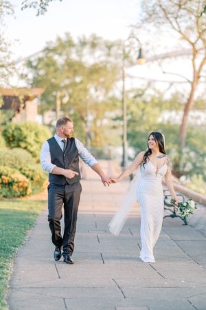 A couple dances playfully on a stone path during a sunset wedding photoshoot.