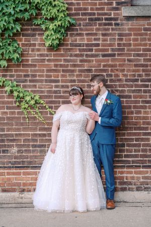 A couple in wedding attire poses against a brick wall with green ivy, captured in a series of candid moments.