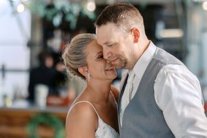 A couple shares an intimate moment during a wedding celebration with soft bokeh lights in the background.