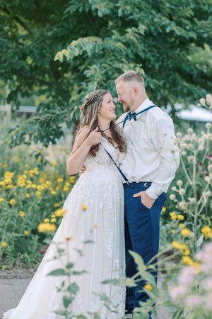 A romantic moment between newlyweds in a garden with yellow wildflowers and greenery.