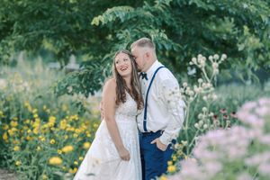 A couple shares romantic moments in a lush garden setting with blooming flowers and greenery during their wedding celebration.