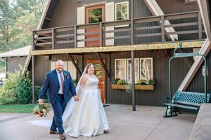 Newlywed couple poses together in front of rustic brown barn during outdoor wedding ceremony.