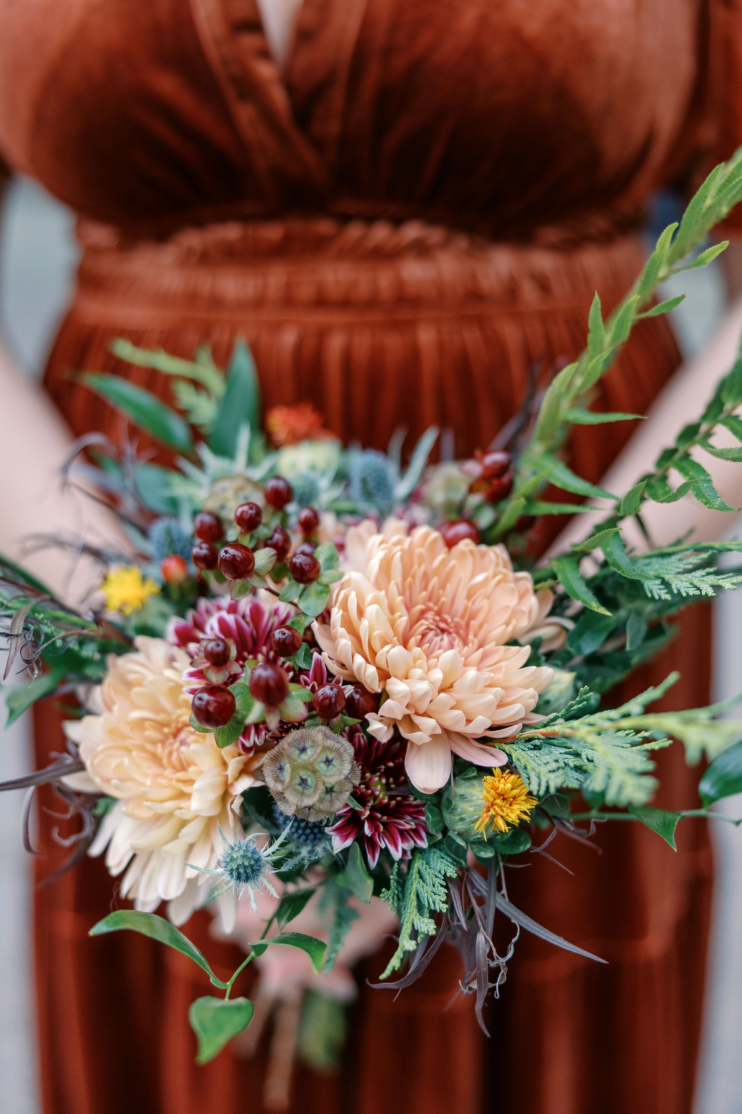 A delicate floral garland with peach dahlias, burgundy blooms, and green foliage creates an elegant decoration.