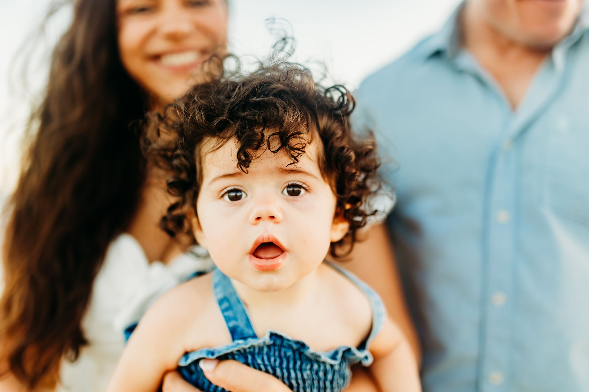 a wide eyed baby girl with lots of curls, looks right at the camera