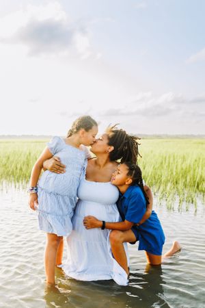 a mother and her two daughters snuggling in the marsh