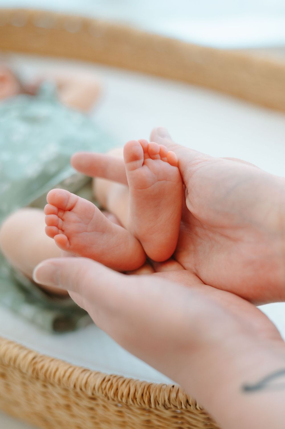 Close-up view of tiny baby feet with delicate toes against a soft blanket background.